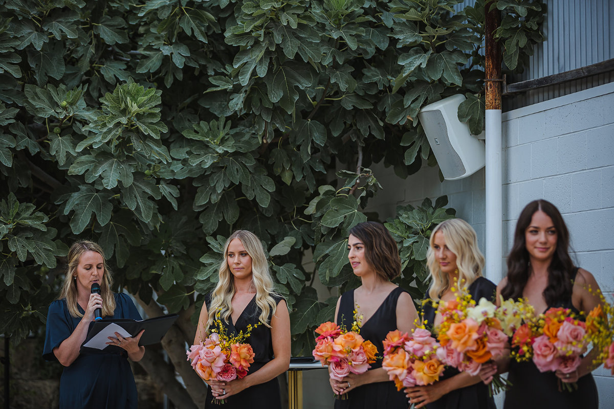 Bridesmaids listening to religious ceremony reading outdoor wedding