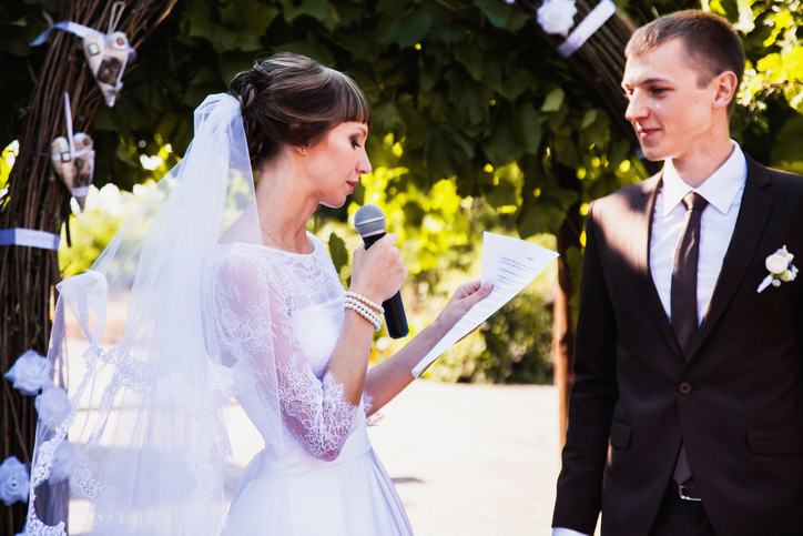 Groom and bride in white dress on background of the arch. Wedding ceremony. Happy family