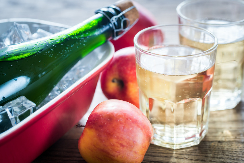 Bottle and two glasses of cider on the wooden background