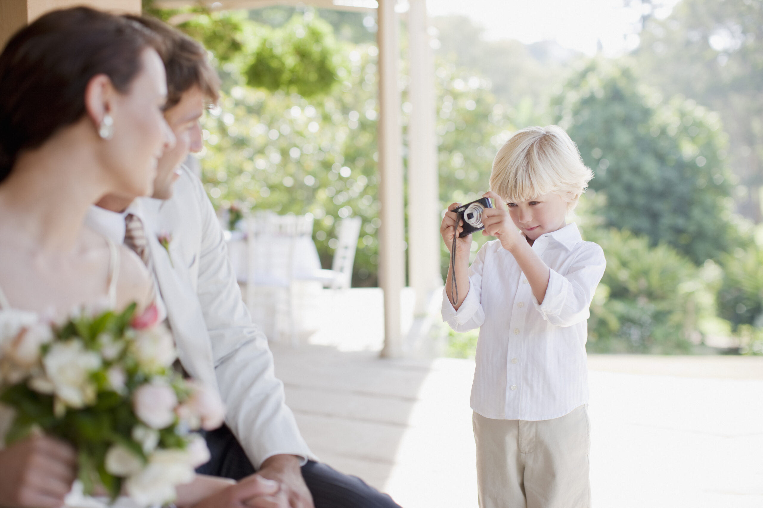 Boy taking picture of bride and groom