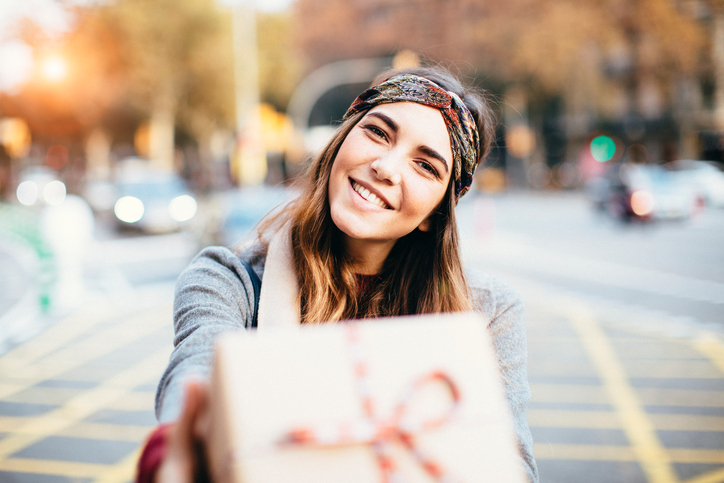 Young beautiful woman handing a present.