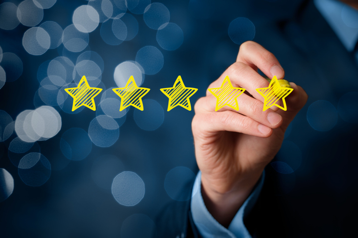 Review, increase rating or ranking, evaluation and classification concept. Businessman draw five yellow star to increase rating of his company. Bokeh in background.