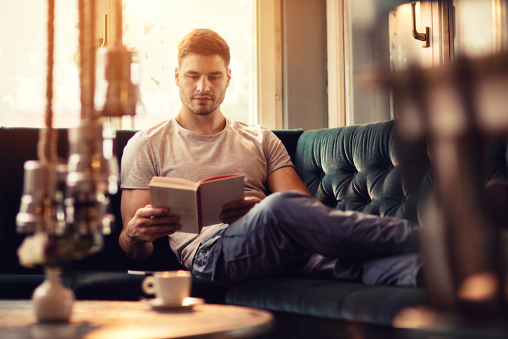 Young man relaxing with a book in the living room.