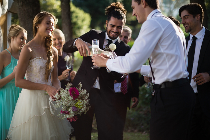 Groom pouring champagne into his friends glasses