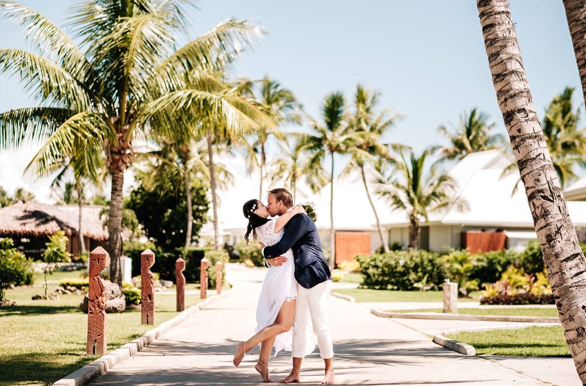 Couple kissing in a tropical setting with palm trees